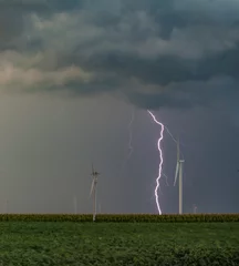 Fotobehang Lightning storm and windmills with dark clouds and green fields © Barry Darnall