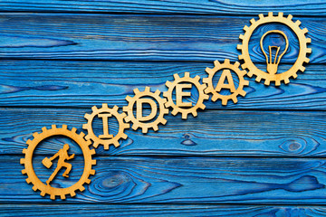 running man, light bulb, gears on wooden background. the concept of the business idea.
