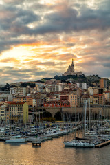 Naklejka premium Sunrise in Marseille Old Port, France with Notre-Dame de la Garde church on the hill and old port
