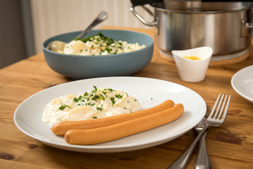 Wiener Würstchen und  Norddeutscher Kartoffelsalat mit Mayonnaise, Ei und Gurke als Mahlzeit auf Holz Tisch