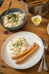 Wiener Würstchen im Topf, Senf und  Norddeutscher Kartoffelsalat mit Mayonnaise, Ei und Gurke als Mahlzeit auf Holz Tisch