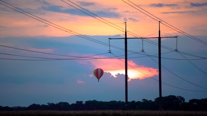 Fantastic view of beautiful hot air balloon flying in glowing sunset sky, beauty