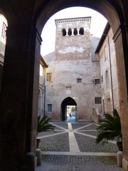 Torre della basilica e monastero  medievale dei Quattro Coronati vista da un arco a Roma in Italia. 