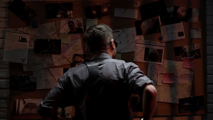 Fototapeta na wymiar Cool male detective looking at investigation board, searching for answers
