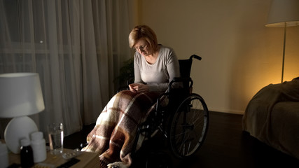 Fototapeta na wymiar Upset lady in wheelchair thinking about children, abandoned patient nursing home