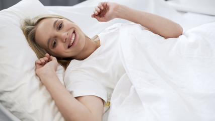 Obraz na płótnie Canvas Healthy sleep on orthopedic mattress, happy teenage girl waking up with smile