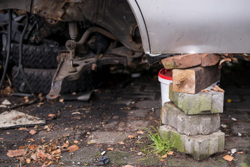 Fototapeta na wymiar Detailaufnahme eines Autos ohne Räder aufgebockt auf Pflastersteine