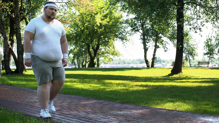 Man walking slowly, exhausted after running, cardio training for weight loss