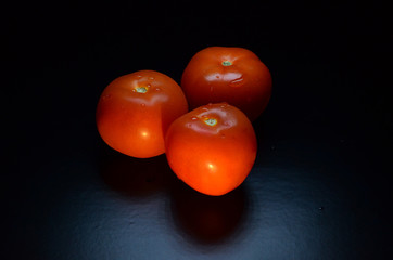 three tomatoes on a black background