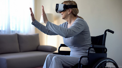 Old handicapped woman enjoying virtual reality in headset, modern technologies