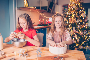 Adorable happy little girls baking Christmas gingerbread cookies in Xmas eve