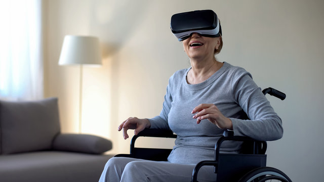 Retired woman in wheelchair wearing vr goggles and enjoying game, technology