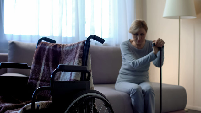 Unhappy Handicapped Senior Woman Looking At Empty Wheelchair, Loneliness