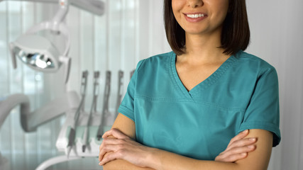Fototapeta premium Smiling female dentist posing for camera, qualified medical care, modern clinic
