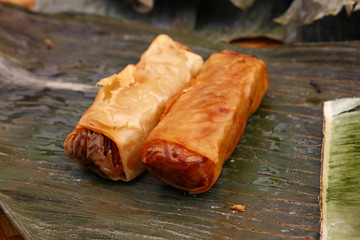 Fried spring rolls served on green banana leaves