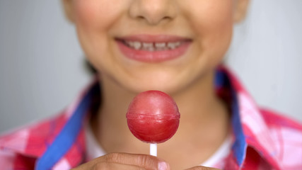 Teenage girl showing lollipop at camera, dental care concept sugar causes caries