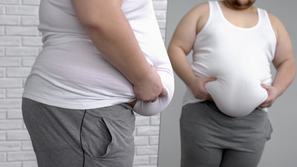Unhappy male holding his fat stomach, desire to lose weight, health problems