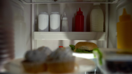 Fototapeta na wymiar Closeup of junk food inside fridge, unhealthy nutrition, high calorie meal