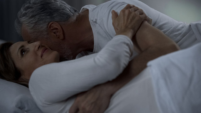 Aged male kissing woman neck, couple hugging and caressing in bed, attraction