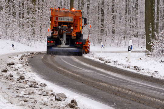 Ein R&auml;umfahrzeug des Winterdienstes r&auml;umt die Stra&szlig;e von Schnee und streut Salz