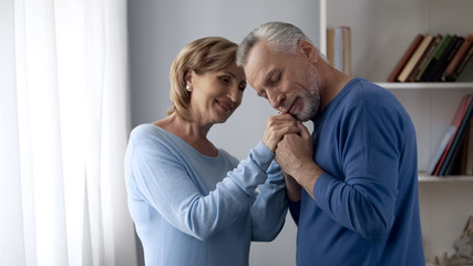 Senior man holding his wife hands, touching silky skin, enjoying tenderness