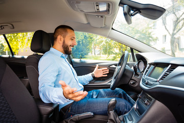 Side view of happy and surprised young businessman driving driverless car