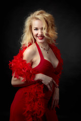 Fototapeta premium Attractive middle age woman in red evening dress with fluffy feather boa.