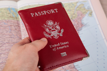 American passport in hand against a geographical map