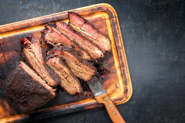 Foto op Plexiglas anti-reflex Traditionele gerookte barbecue Wagyu beef brisket als stuk en gesneden aangeboden als bovenaanzicht op een oude snijplank met kopieerruimte rechts © HLPhoto
