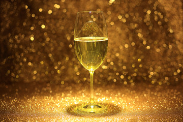 Kieliszek z szampanem na złotym błyszczącym tle.