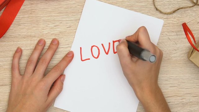 Woman writing love word on paper, romantic relationship between man and woman