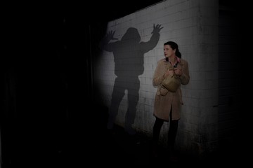 Frau wird auf dunkler Straße  von einem bedrohlichen Schatten verfolgt