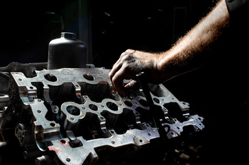 Mechanic hand checking and fixing a broken car in car service garage