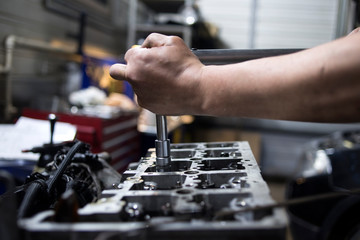 Fototapeta na wymiar Mechanic hand checking and fixing a broken car in car service garage