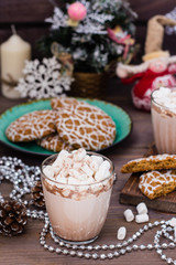 Hot cocoa with marshmallows in glasses and christmas cookies on a plate on the wooden table in Christmas decorations