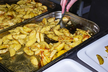 The cook prepares fried potatoes on a baking sheet