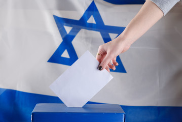 Israeli woman votes at a polling station on election day.Close up of hand with white votes paper on...