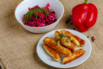 Breaded cheese and kefir sticks. Made from cheese, flour and kefir. Served with red salad.