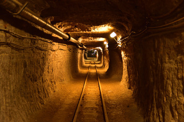 Underground workings in salt mine with pipelines and railway - obrazy, fototapety, plakaty