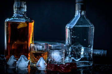 Vodka and whiskey in the bottle, vodka and whiskey in glass with ice, alcoholic drink