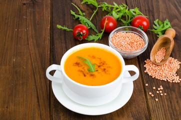Red lentil soup in plate on wooden background