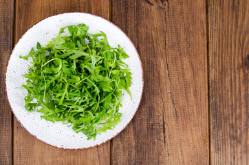 Vegetarian dish, plate with green arugula on wooden table