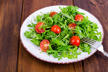 Plate with light dietary salad of arugula and cherry tomatoes