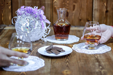 Fototapeta premium Romantic date night. Holding glasses of brandy, say a toast
