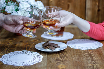 Fototapeta na wymiar Romantic date night. Holding glasses of brandy, say a toast