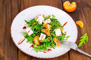 Delicious fruit and vegetables salad. Tangerine, feta cheese, arugula and chia seeds in plate. Healthy food concept