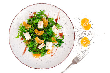 Delicious fruit and vegetables salad. Tangerine, feta cheese, arugula and chia seeds in plate. Healthy food concept