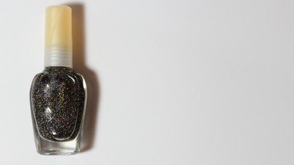 Bottle of black glittering nail polish. Space in blank to insert text about nail polish, vanity, beauty, trends