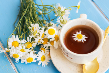 cup of herbal chamomile tea with fresh daisy flowers on wooden background. doctor treatment and...