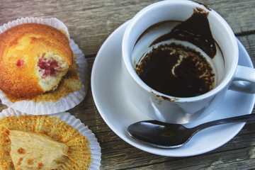 A Cup finished of coffee with a bitten cake, close-up